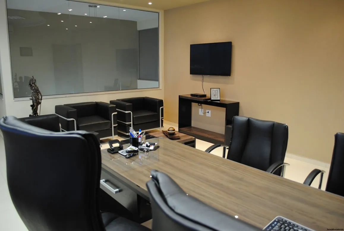 Sala de reuniões com mesa de madeira e televisão